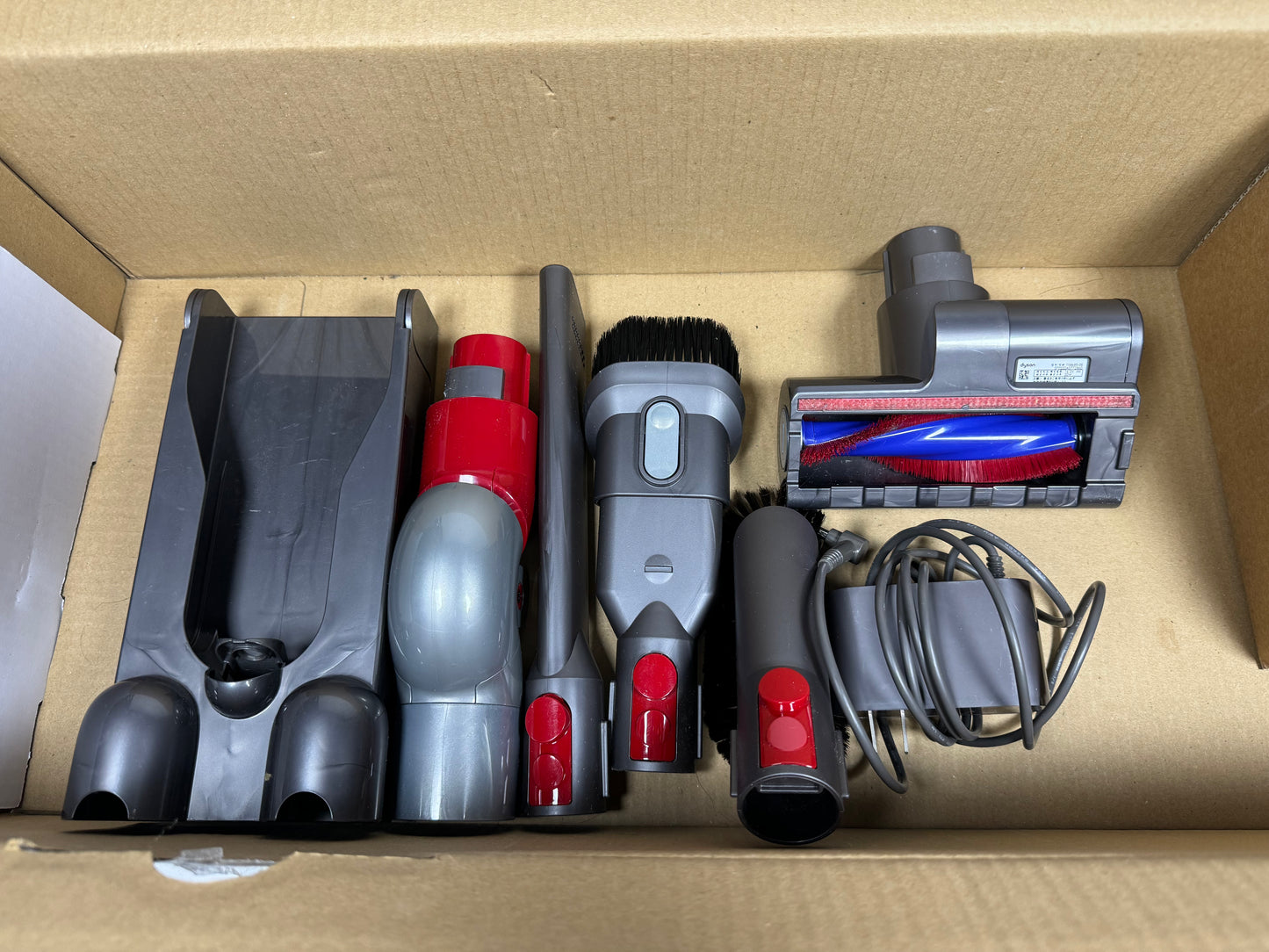 Collection of vacuum cleaner attachments in a cardboard box