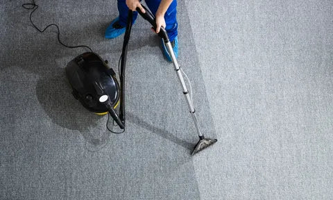 Person cleaning a carpet with a vacuum cleaner