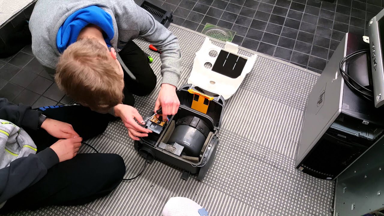 Two people working on a device on a tiled floor