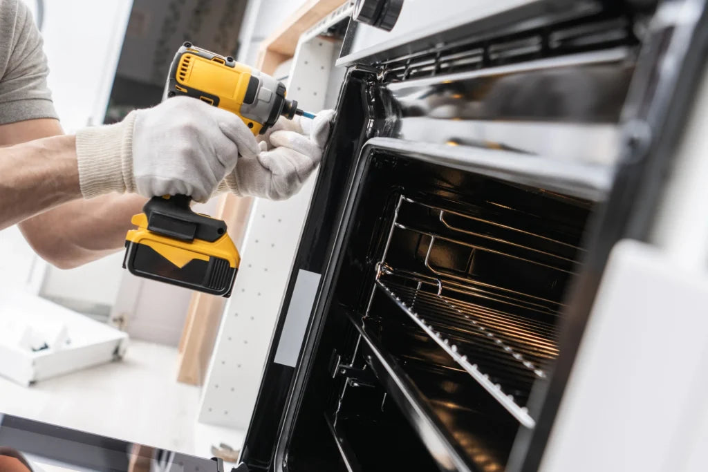 Person using a power drill to work on an open oven