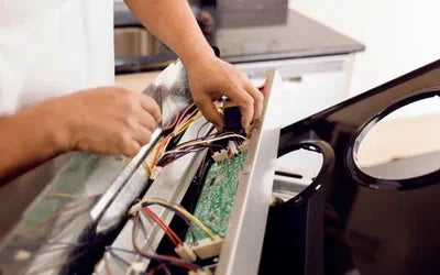 Person working on electrical components of a piece of equipment in a kitchen setting