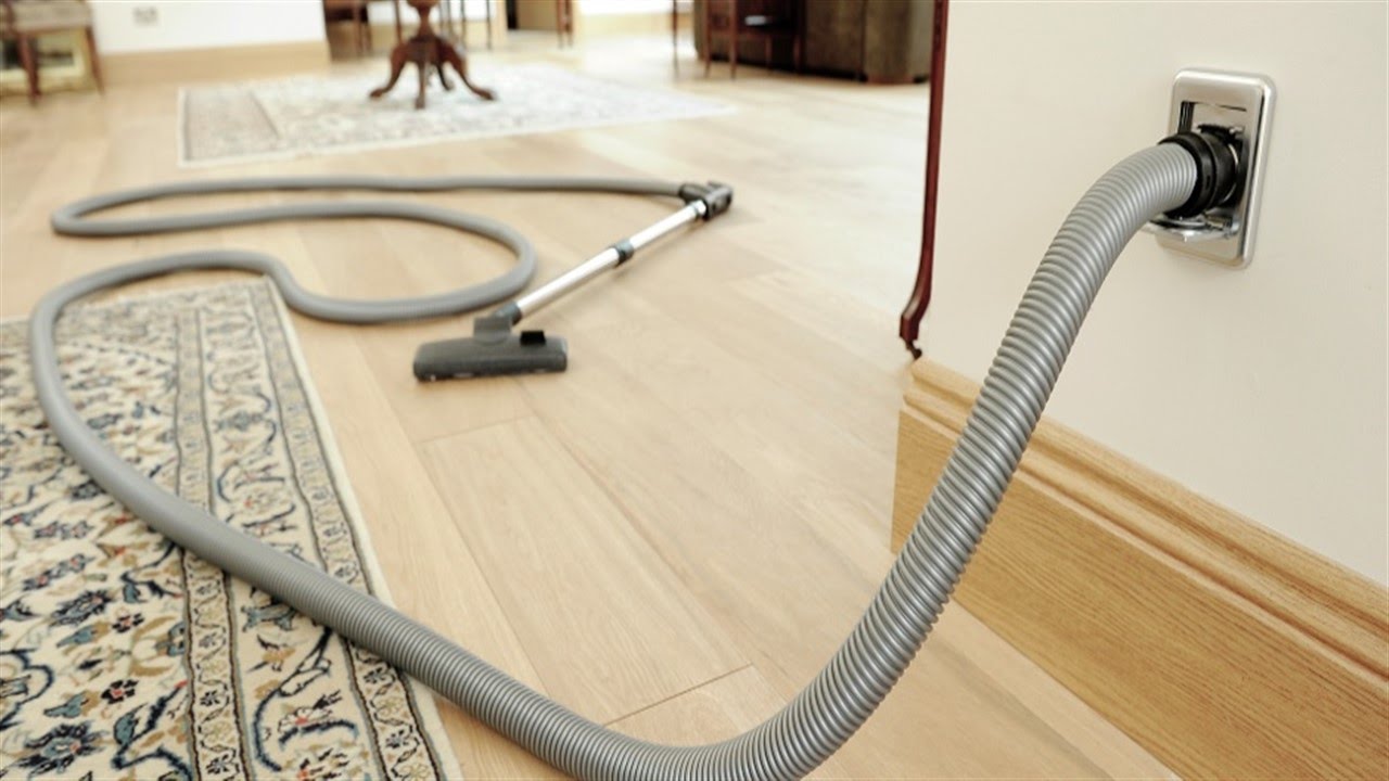 Vacuum cleaner with hose on a wooden floor with a rug
